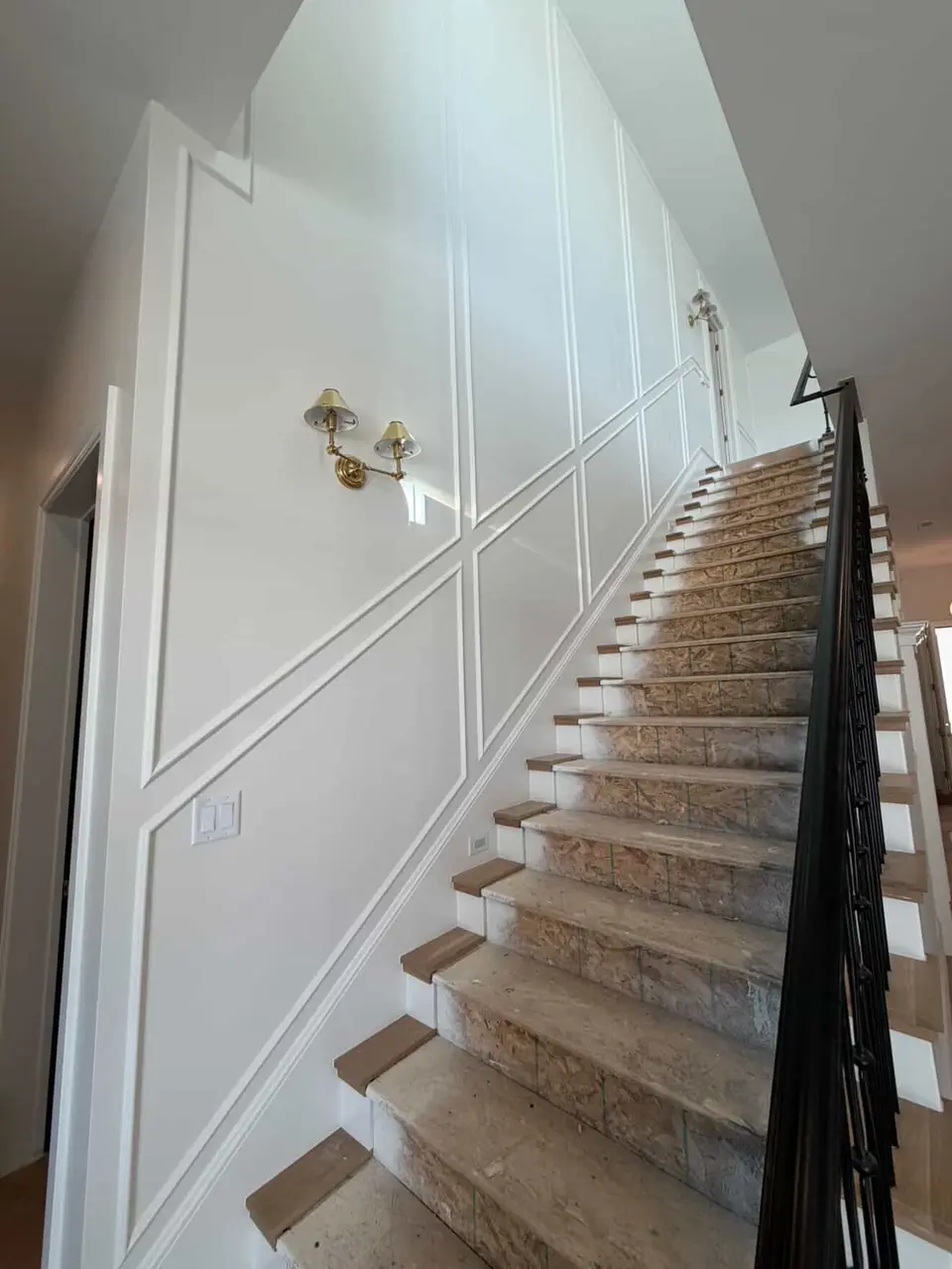 Stair wall panel molding and tread installation in progress